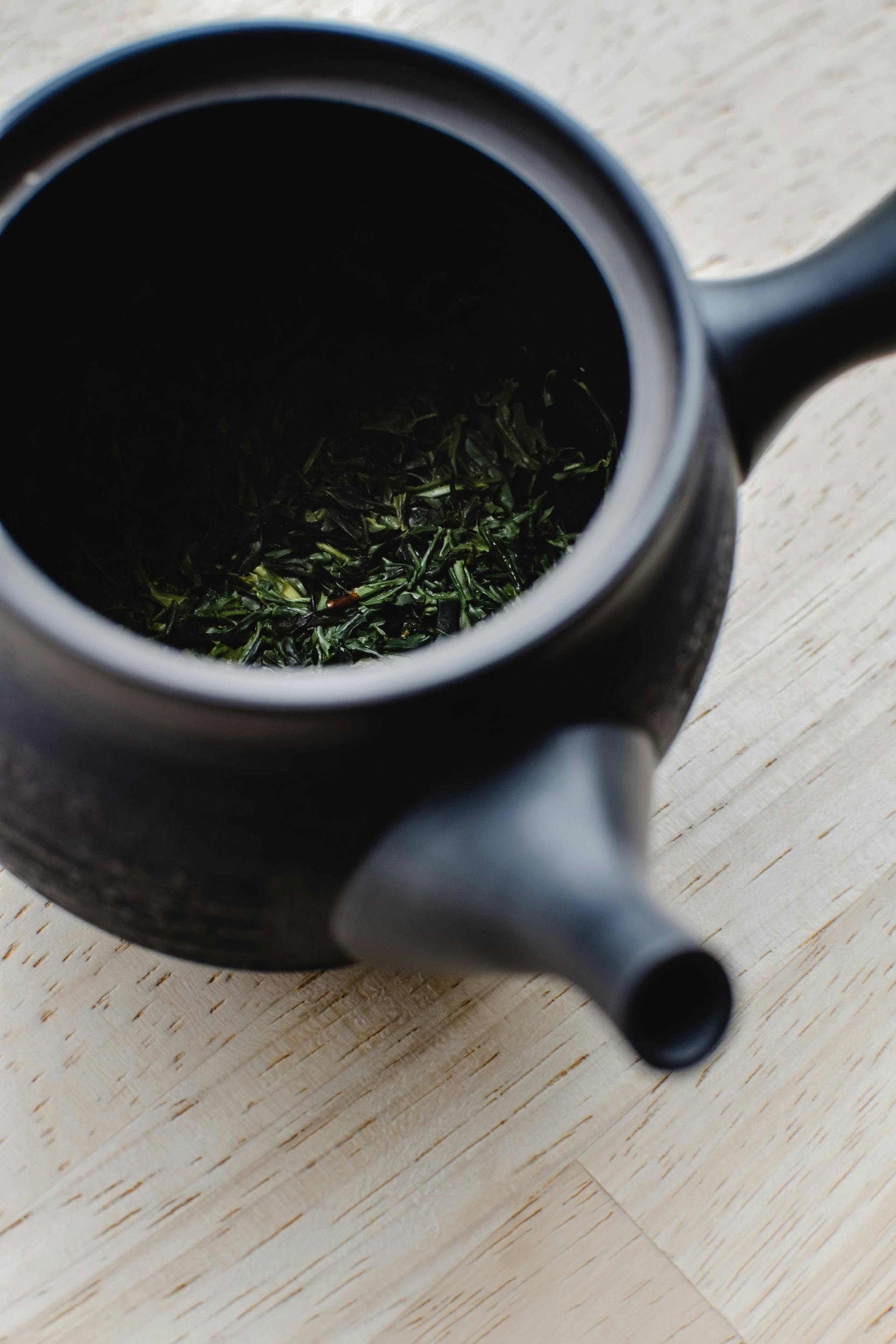 Background image - green tea leaves inside black kyusu